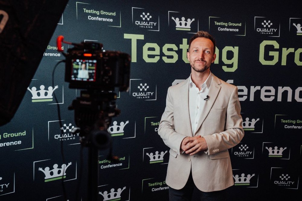 Tomasz Stelmach in front of the Testing Ground Conference press wall